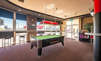 a billiards room with multiple pool tables , air hockey tables , and arcade games , as well as a bar area with a pool table at The Lighthouse Hotel