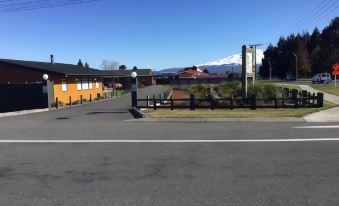 a street with a road in the foreground and a building with a fence on the side at Waiouru Welcome Inn
