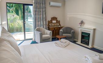 a cozy bedroom with a bed , two chairs , a fireplace , and a door leading to a balcony at Tamar House