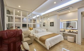 a modern bedroom with a large bed , a couch , and a tv . the room has white walls and hardwood floors at Dubai Hotel