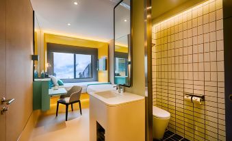 a modern bathroom with yellow walls , white tiles , and a large window , along with a bed and a desk at The Upper House Hotel