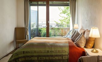 a cozy bedroom with a bed , two chairs , and a window overlooking a balcony , under the glow of warm light at The View