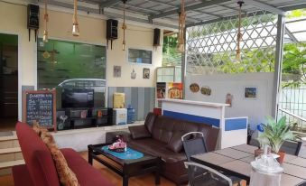 a living room with a couch , chairs , and a tv . also a dining table in the room at Bakom Inn Syariah