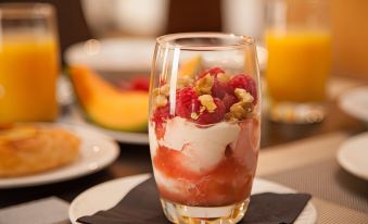 a dining table with a glass of yogurt and fruit , accompanied by a glass of orange juice at Wine Country Motor Inn