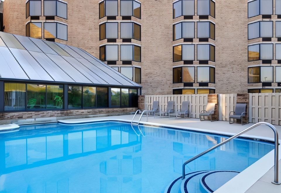 a hotel with a large swimming pool surrounded by lounge chairs and umbrellas , providing a relaxing atmosphere for guests at DoubleTree by Hilton Hotel Murfreesboro