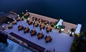an aerial view of a large outdoor dining area with tables , chairs , and umbrellas by a body of water at Seehotel Grüner Baum