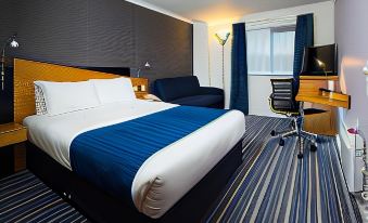 a hotel room with a bed , desk , and chair , along with a blue and white color scheme at Holiday Inn Express Stafford