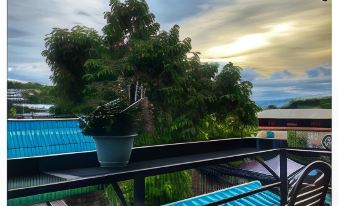 a balcony with a view of a blue sky and trees , featuring a potted plant at The One House