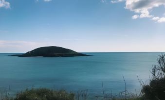 a serene scene of a body of water with an island in the distance , surrounded by lush greenery at Bridgeside Guest House