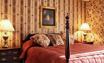 a bedroom with a large bed , red comforter , and two lamps on either side of the bed at Waynebrook Inn