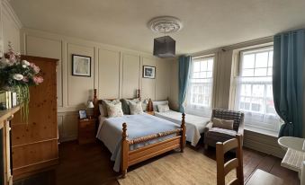 a spacious bedroom with two beds , one on the left side of the room and the other on the right side at The Mansion House Hotel