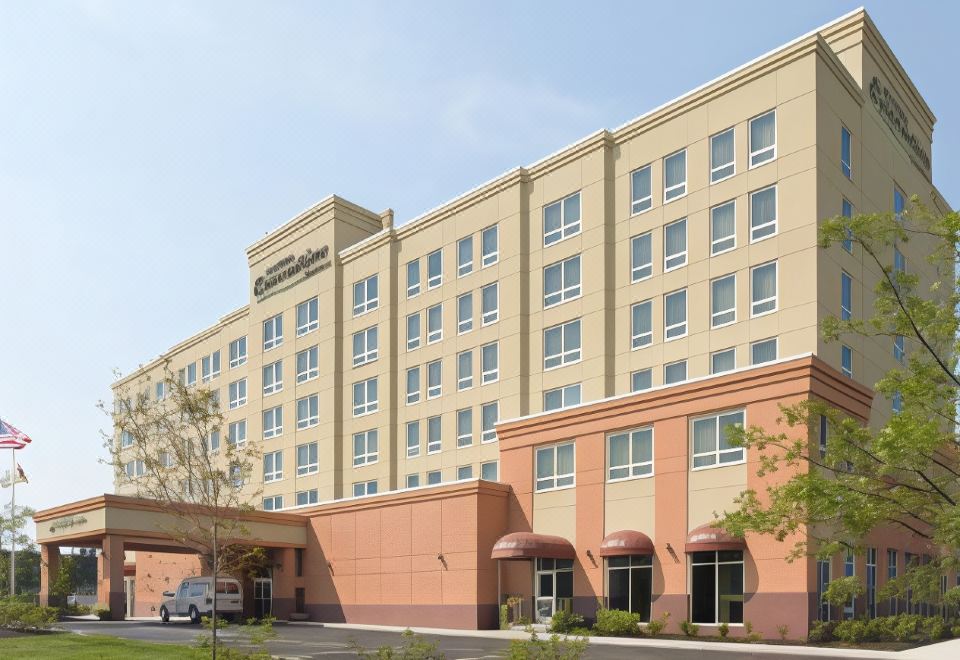 a large hotel building with a pink and beige color scheme , situated next to a road at Hotel Executive Suites