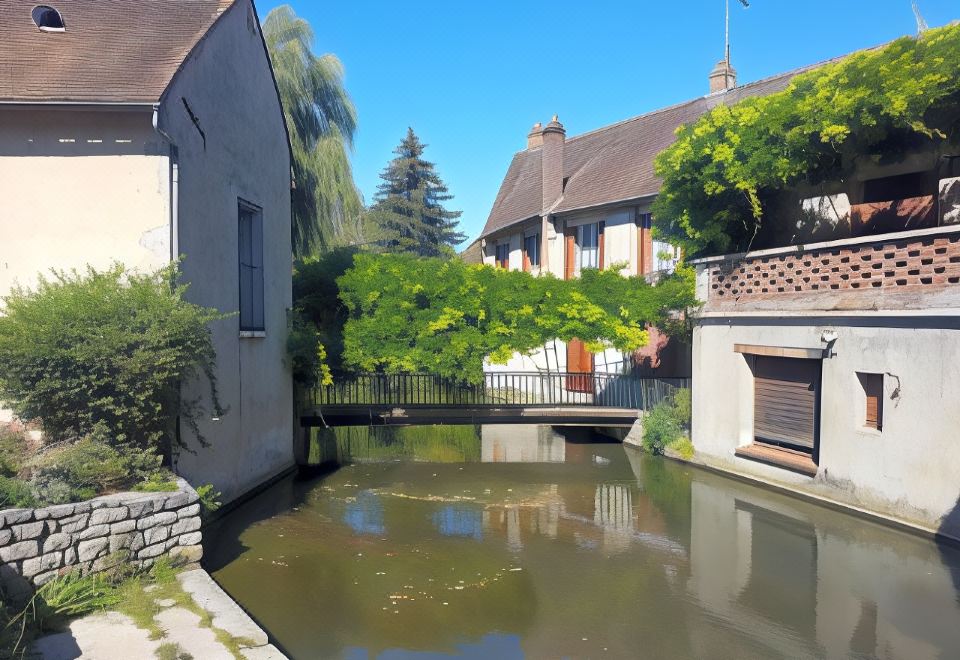 a small canal with a small bridge over it , surrounded by houses on both sides at Logis Hotel Restaurant de l'Abbaye