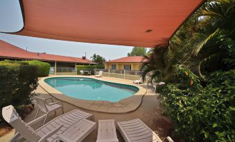 a backyard with a swimming pool surrounded by lounge chairs and umbrellas , providing a relaxing atmosphere at Emerald Explorers Inn