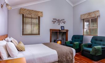 a bedroom with a bed , two chairs , and a fireplace in the center of the room at Cypress Ridge Cottages