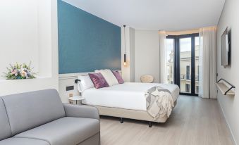 A modern bedroom features white walls, blue accents, and a large window above the double bed at Arcelon Hotel
