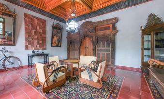 a living room with a wooden table and chairs , large wooden doors , and a red tiled floor at Super OYO Collection O 2383 Andongkoe 64 Salatiga