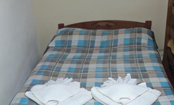 a neatly made bed with a checkered bedspread and two white towels folded on top at Alquimia