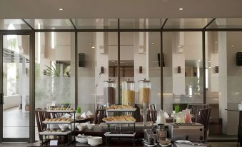 a buffet - style dining area with a variety of food and drinks on display , including bowls , cups , and bottles at The Pade Hotel