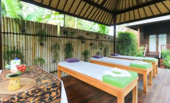 a group of massage tables placed on a wooden deck , surrounded by greenery and bamboo fencing at Coconut Boutique Resort