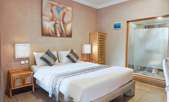 a large bed with white linens is in a room with wooden furniture and a painting on the wall at Coconut Lodge