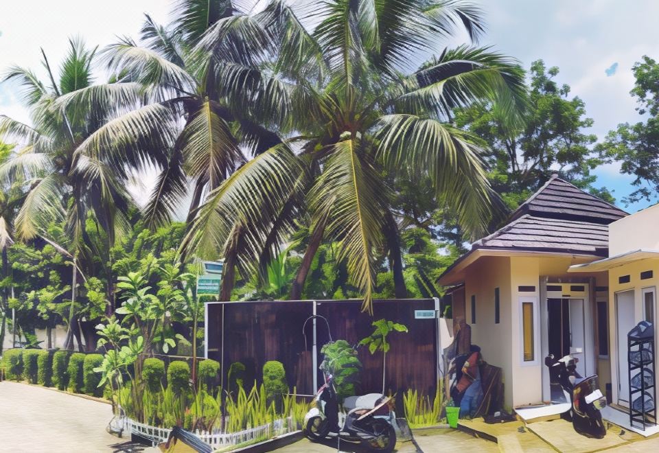 a man is standing next to a house with a motorcycle parked in front of it at Bakom Inn Syariah