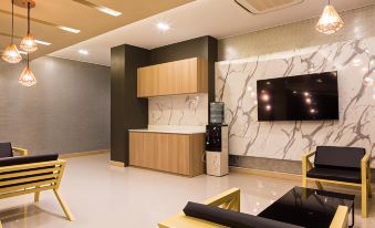 a modern living room with a large flat - screen tv mounted on the wall , along with a dining table and chairs at Grand Inter Hotel