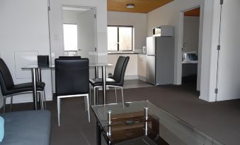 a modern kitchen and dining area with a glass table , black chairs , and stainless steel appliances at Pinewood Motels