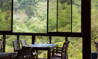 a dining table with chairs is set up in a room with large windows overlooking a forested area at Hotel Quelitales