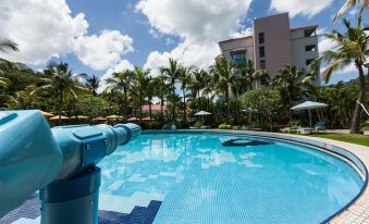 a large swimming pool with a blue water slide and surrounding facilities in front of tall buildings at Hotel Cham Cham Tainan