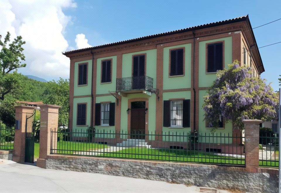 a large green and brown building with a black fence in front of it , surrounded by a grassy area at La Fornace