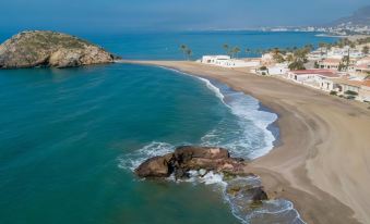 an aerial view of a beautiful beach with clear blue water , white sand , and rocky shoreline at Hotel Dos Playas