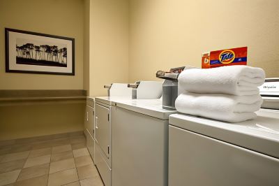 a laundry room with white washing machines , dryers , and towels , along with a box of detergent on the counter at Country Inn & Suites by Radisson, Watertown, SD