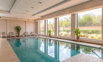 an indoor swimming pool surrounded by windows , allowing natural light to fill the space at Sol Oasis Marrakech - All Inclusive