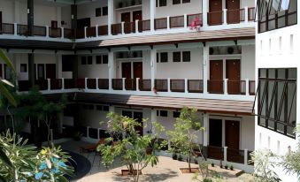 a courtyard with multiple balconies , trees , and a seating area in front of a building at Laut Biru Resort Hotel