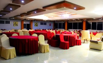 a large banquet hall with multiple tables covered in red tablecloths and chairs arranged for a party at Big Hotel