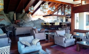 a modern , spacious living room with wooden floors and furniture , including two sofas and a dining table at Seronera Wildlife Lodge