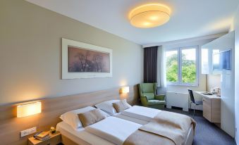 a modern hotel room with two beds , a window , and a painting on the wall at Ahotel Ljubljana