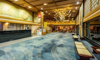a large , well - lit hotel lobby with high ceilings , multiple seating areas , and a reception desk at Zazan Minakami