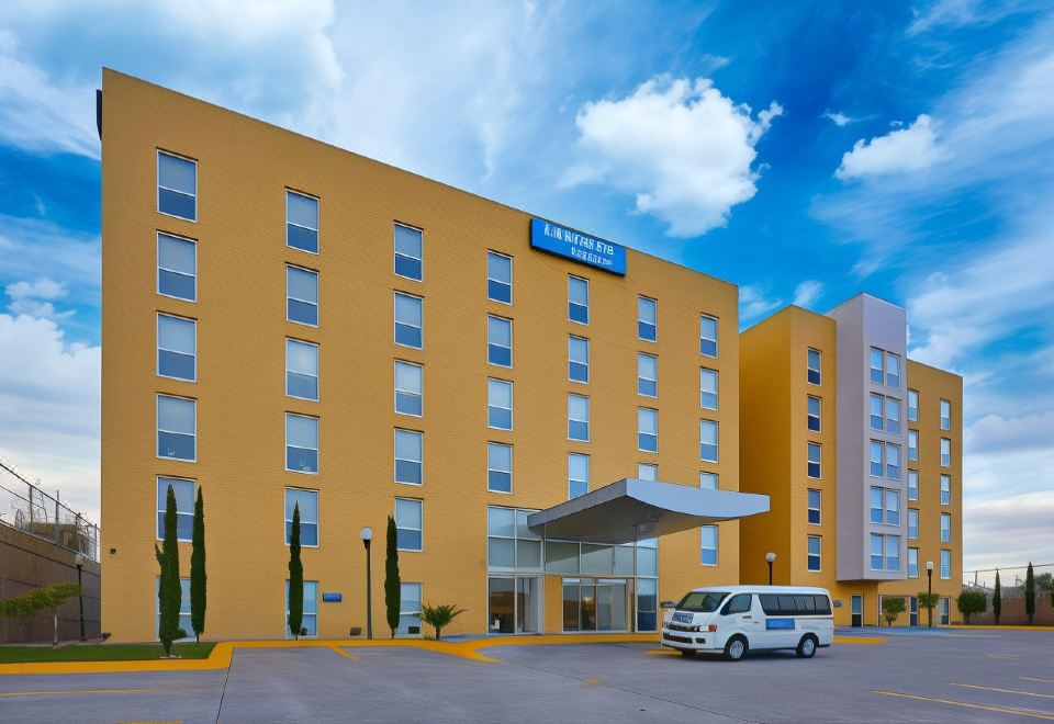 a large hotel building with a yellow facade and a white van parked in front at City Express by Marriott Nogales