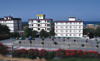 a large hotel building surrounded by trees , with a parking lot in front of it at Hotel Califfo