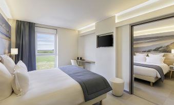 a modern hotel room with a large bed , white walls , and a tv mounted on the wall at Best Western Hotel le Semaphore