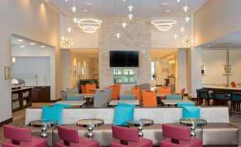 a modern hotel lobby with various seating options , including couches and chairs , as well as a television mounted on the wall at Homewood Suites by Hilton Allentown Bethlehem Center Valley