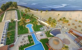 a bird 's eye view of a beach resort with a pool and palm trees , surrounded by grass and trees at Sunset Beach Hotel