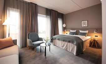 a modern bedroom with a large bed , a chair , and a flat - screen tv . also a potted plant in the room at Hotel Odeon