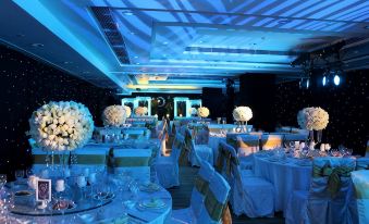 A ballroom is arranged for an event, featuring blue lighting and tables placed in the center at Jinfan Wanyuan Hotel