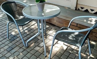a small outdoor table with two chairs , situated on a brick patio near a white building at Sweet Home Alibama