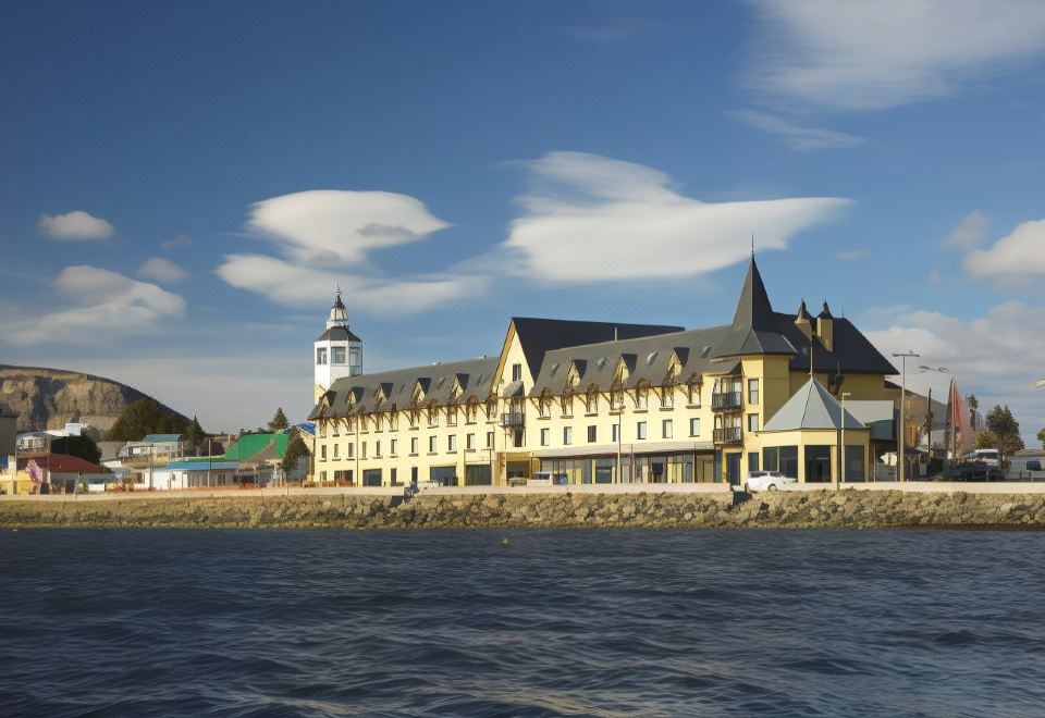 a large building with a clock tower is situated on the waterfront , overlooking a body of water at Hotel Cabo de Hornos