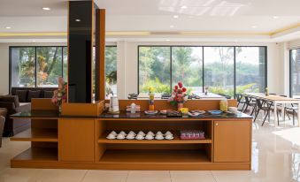 a dining room with a table and chairs , as well as a buffet filled with various food items and utensils at B2 Sriracha Premier Hotel