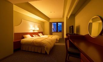 a hotel room with two beds , a desk , and a window , all lit by warm lights at Hotel Verde